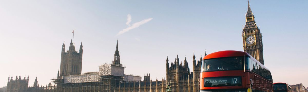 A view of the House of Parliament and Big Ben in London with an iconic London red bus in the foreground