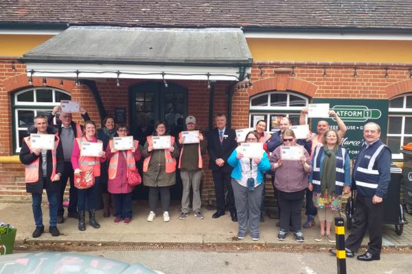 Group standing outside Shawford station cafe waving certificates