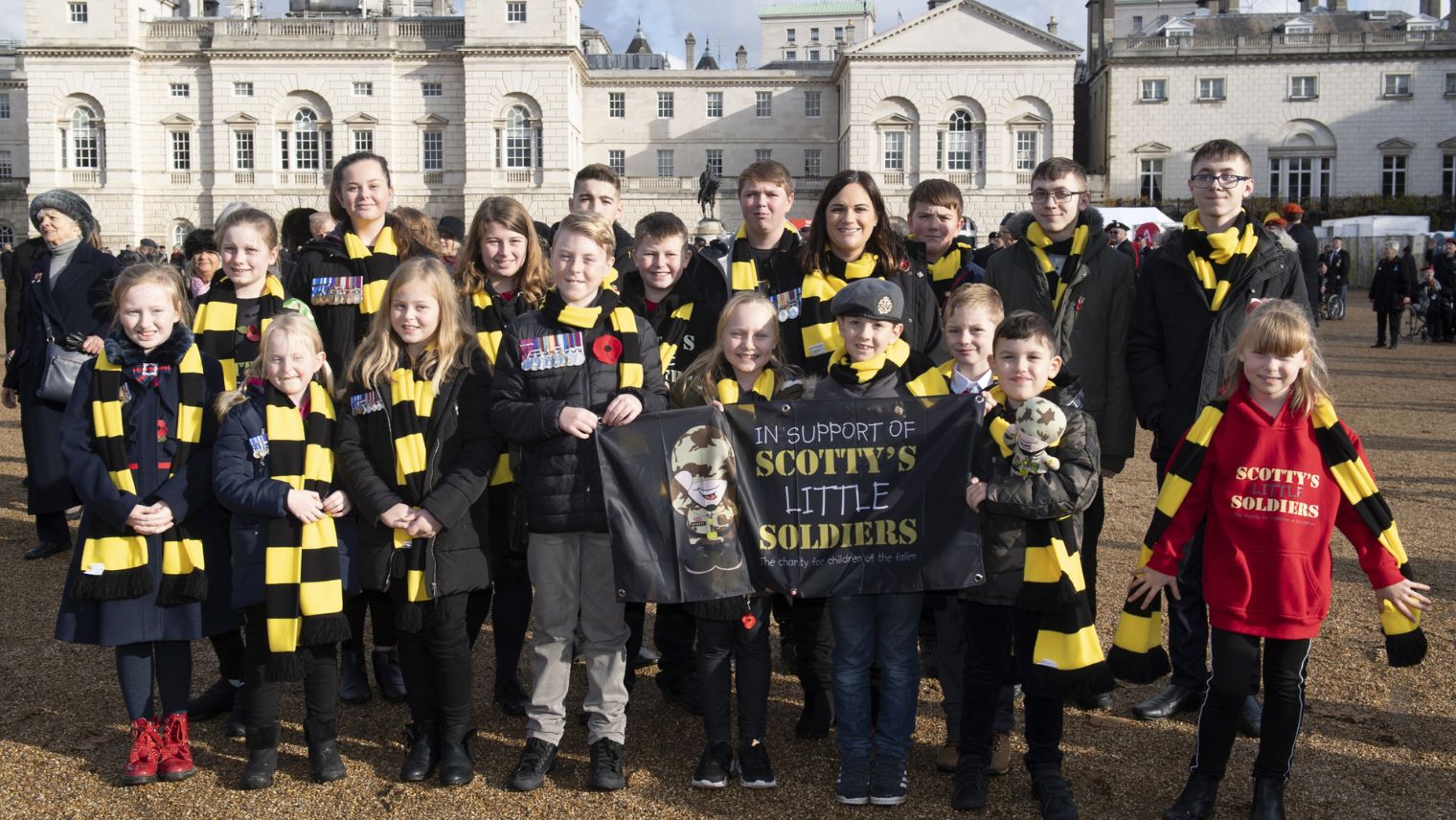 Group of children wearing scarves holding a sign saying Scotty's Little Soldiers