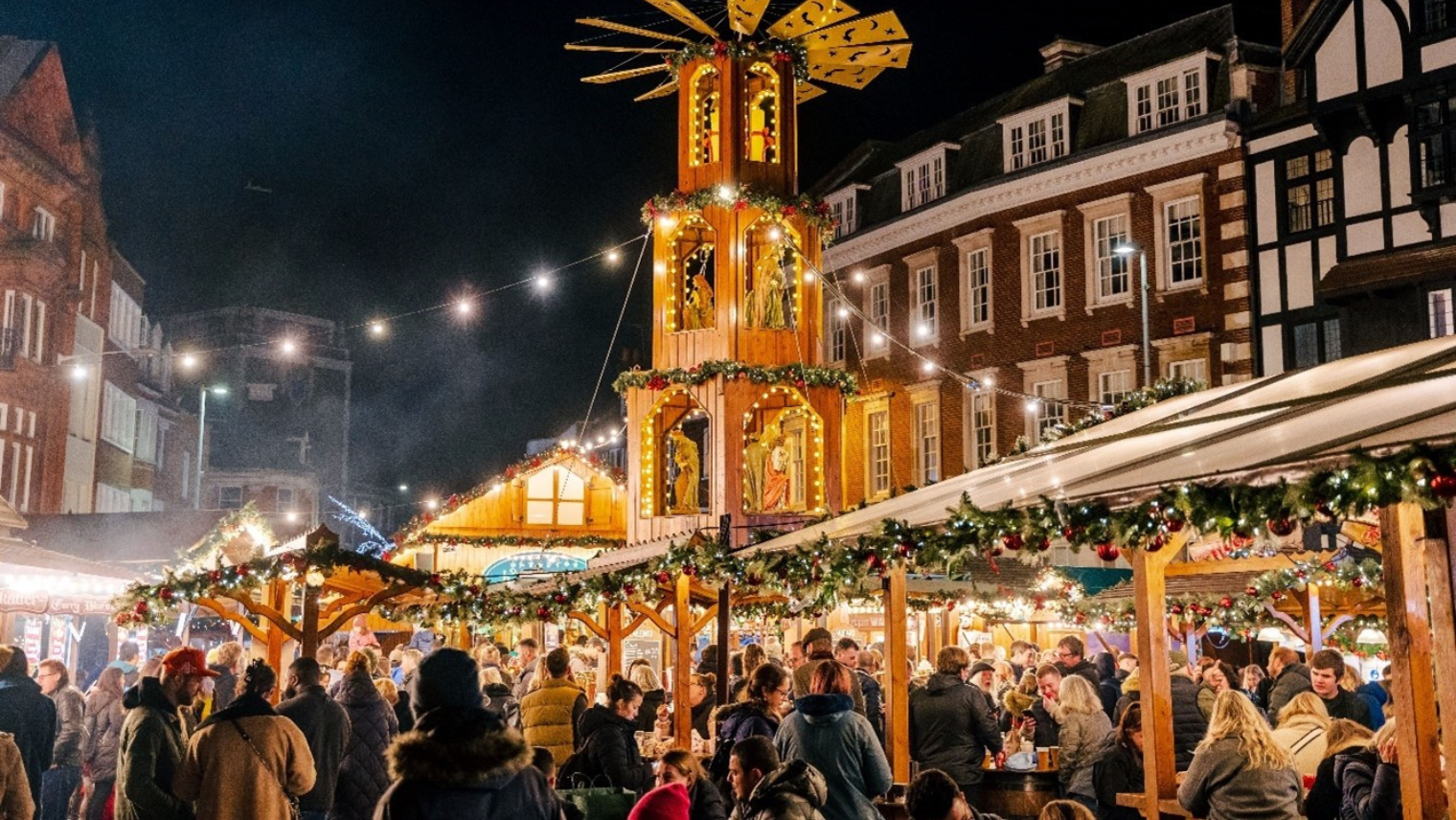 A group of people at Christmas market stalls. 