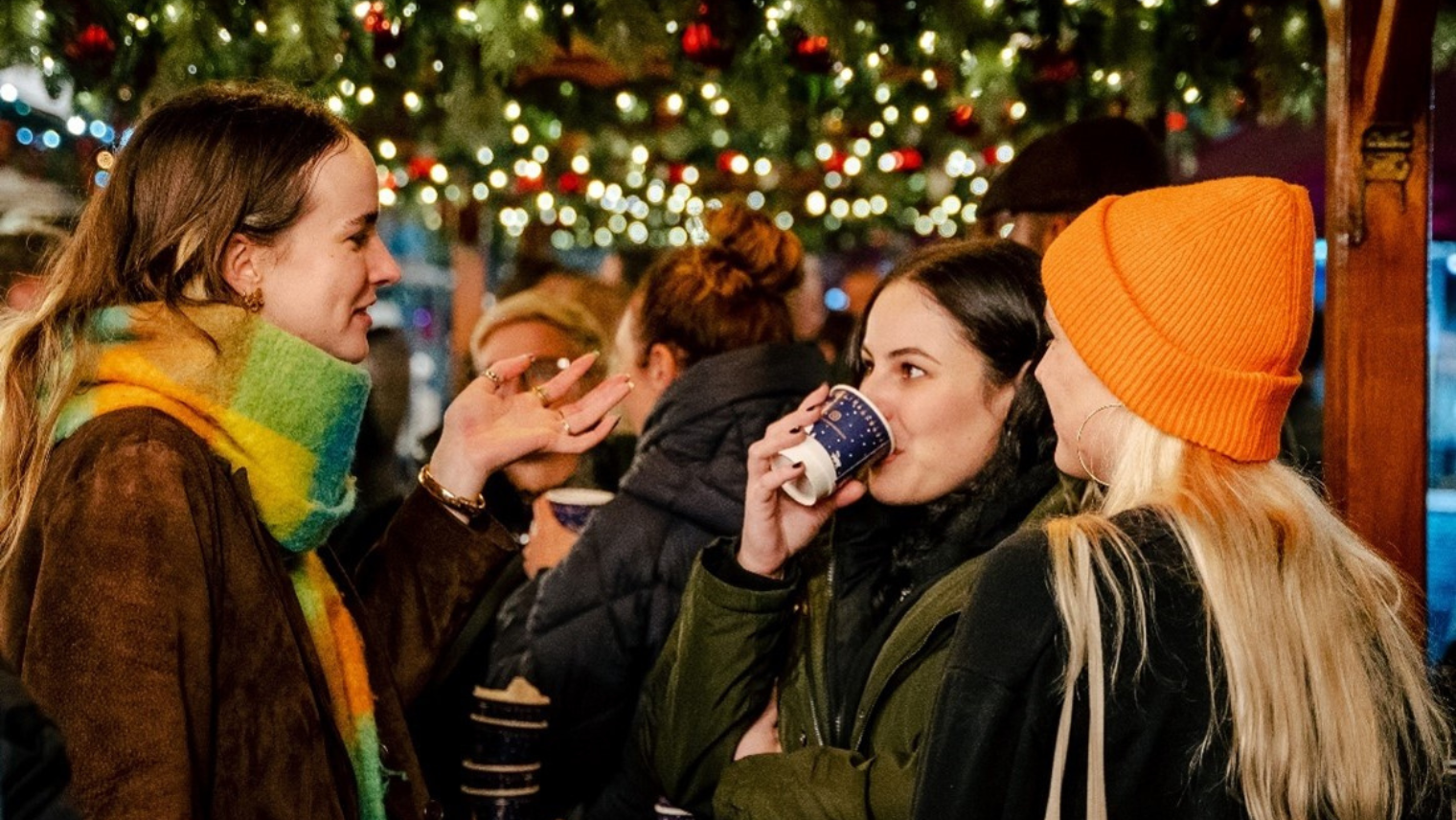 a group of women talking and drinking a warm drink