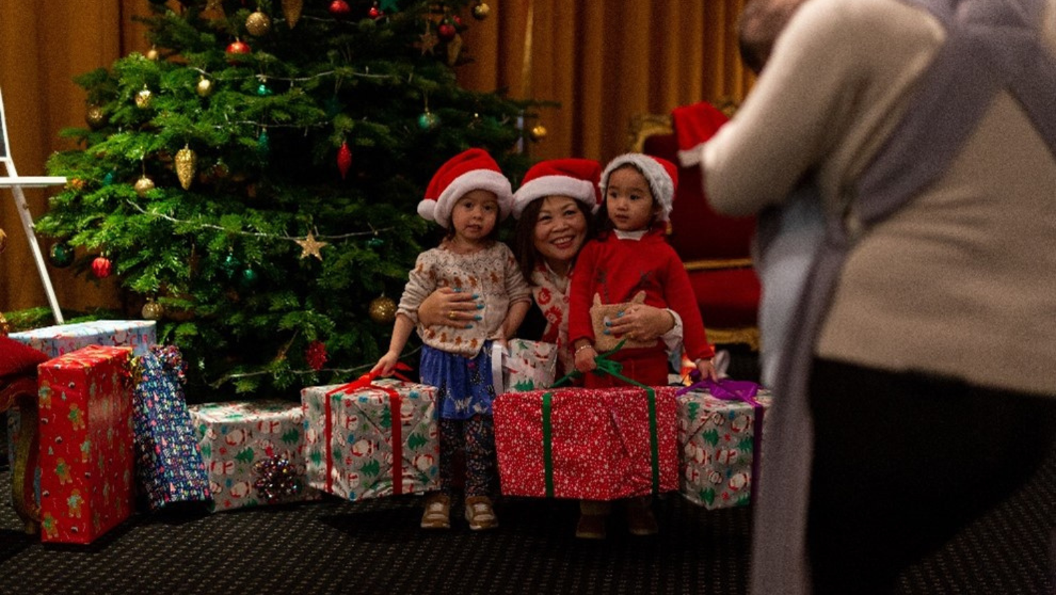 Families posing for photos by a Christmas tree