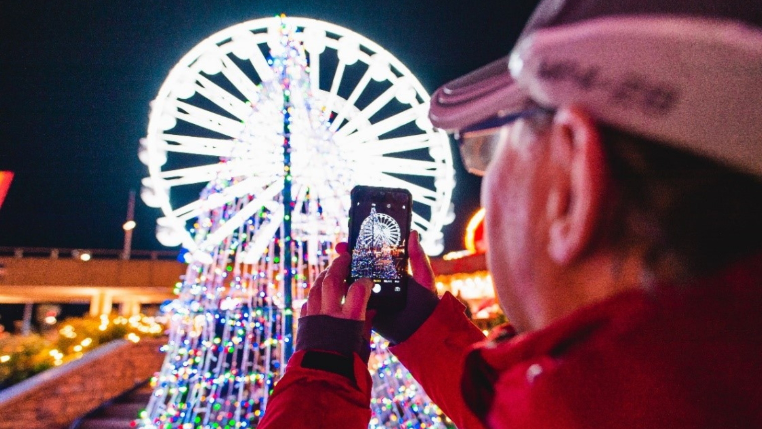 A person taking a picture of a Ferris wheel