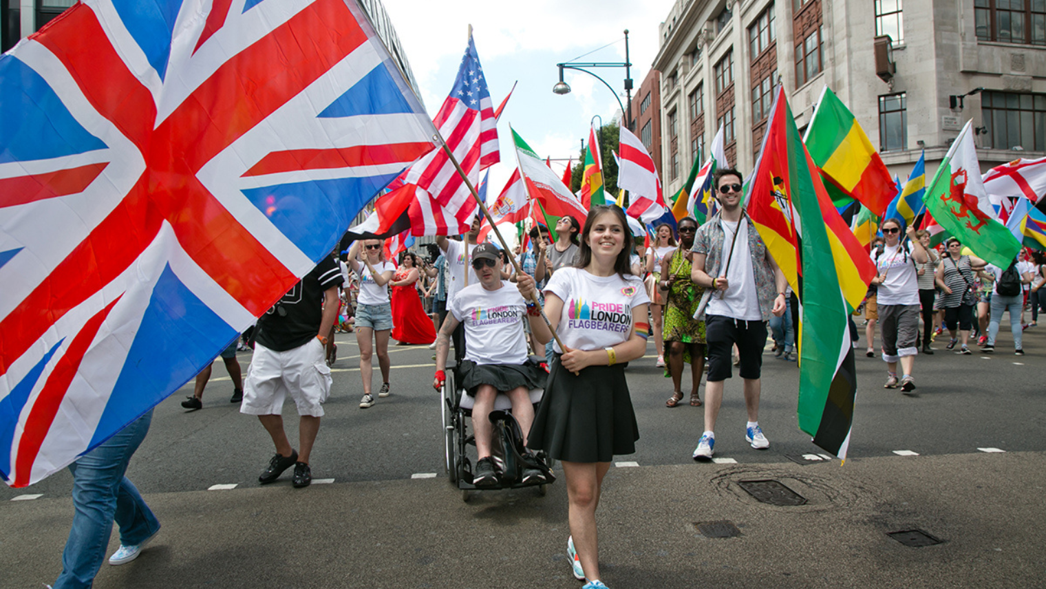 Image of people walking the streets at London Pride waving flags of their home country