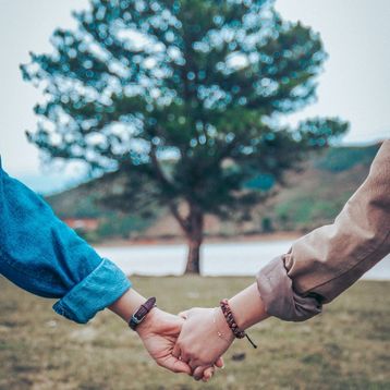 Couple holding hands with a tree in the background