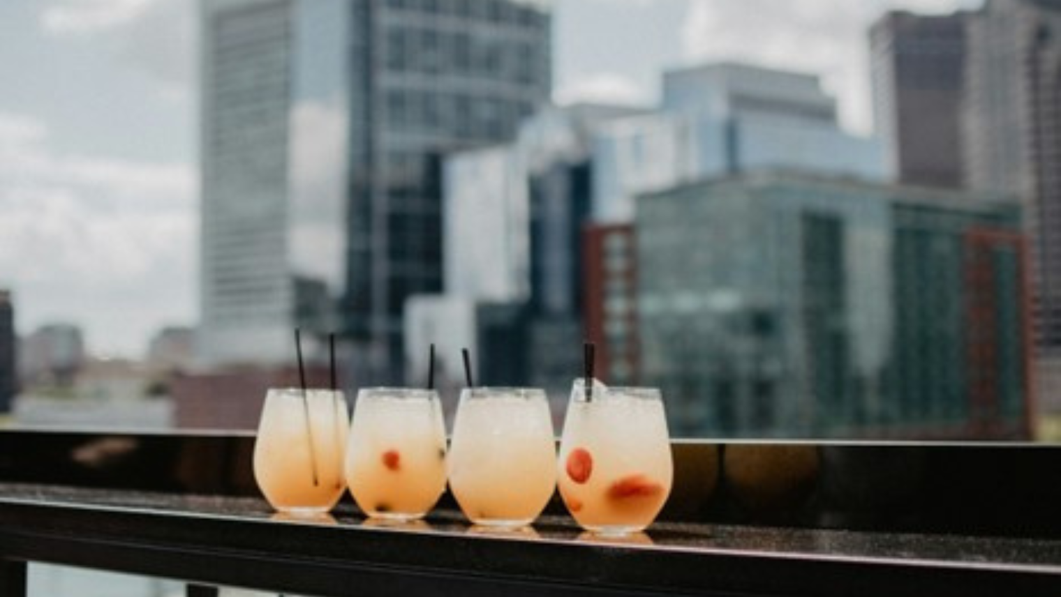 4 cocktails placed on a table overlooking London's skyline