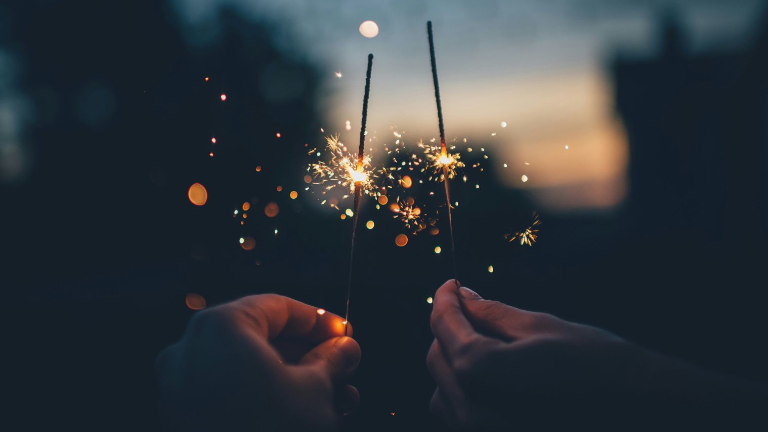 Two hands holding up sparklers together