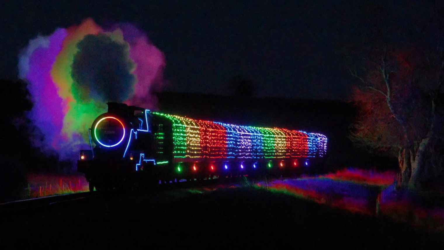 An illuminated steam train on The Watercress Line